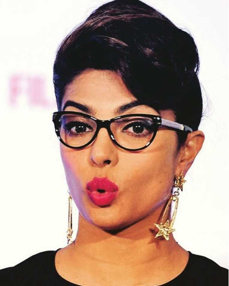 PRIYANKA CHOPRA Solving the question of whether you can wear earrings with glasses (the answer is yes!), PC went all out with a pair of big gold danglers, a bright pink lip and stark black spectacles.